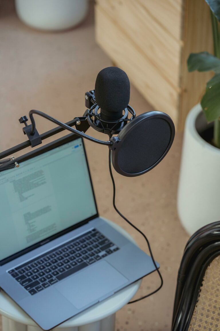 Podcasts A modern podcast setup featuring a laptop and studio microphone on a desk, ideal for digital media production.